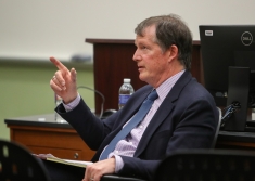 man in suit seated and pointing in classroom