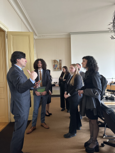group of men and women standing in business suits listening to man
