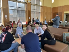 groups of people seated and talking with each other in large wood-paneled room