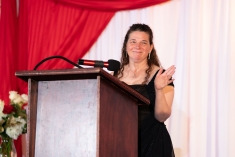 woman in black dress smiling and standing at podium