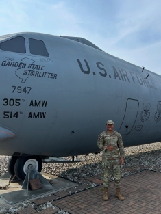 man in military fatigues standing next to huge U.S. Air Force plane