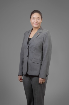 woman in gray suit standing, grinning and smiling